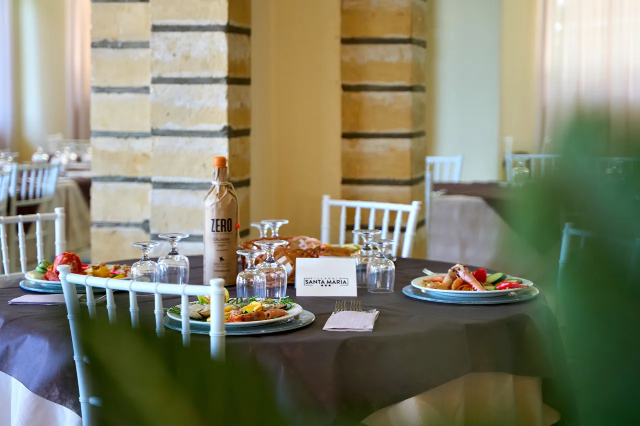 Tavolo da ristorante apparecchiato con piatti di pesce e colonne in pietra
