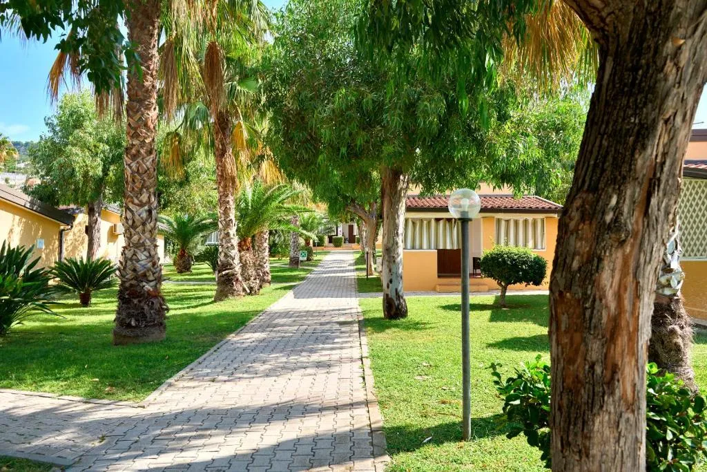 Vialetto pedonale tra palme e bungalow immersi nel verde