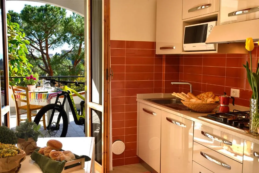 Cucina con piastrelle arancioni, fornelli a gas e microonde, affacciata su un balcone con bicicletta