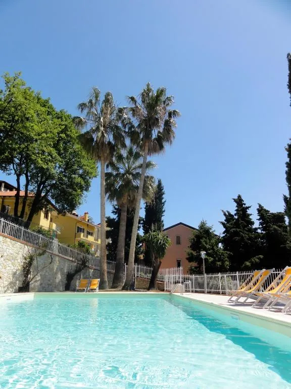 Piscina esterna con acqua azzurra, lettini gialli e palme sotto cielo limpido