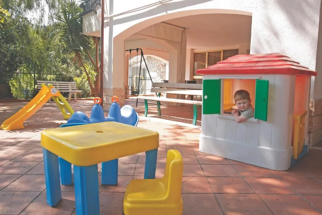 Area giochi per bambini all'aperto con casetta colorata, scivolo, tavolino e altalena
