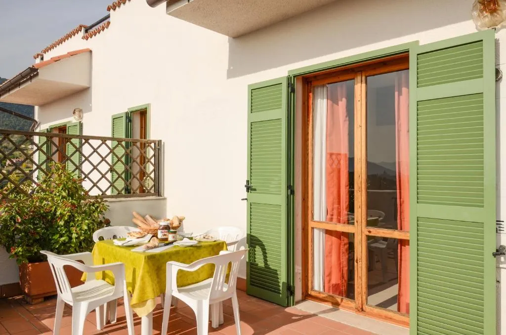 Terrazza privata con tavolo apparecchiato per la colazione e persiane verdi su una porta finestra