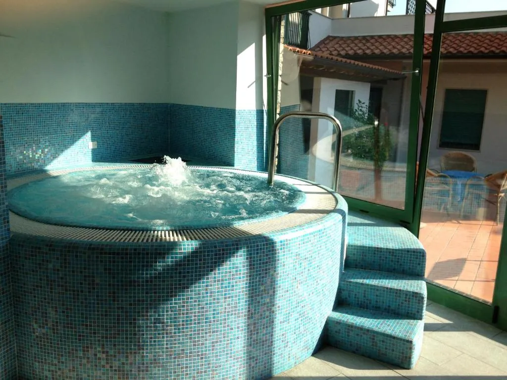 Vasca idromassaggio rivestita in mosaico azzurro con vetrate affacciate sul cortile