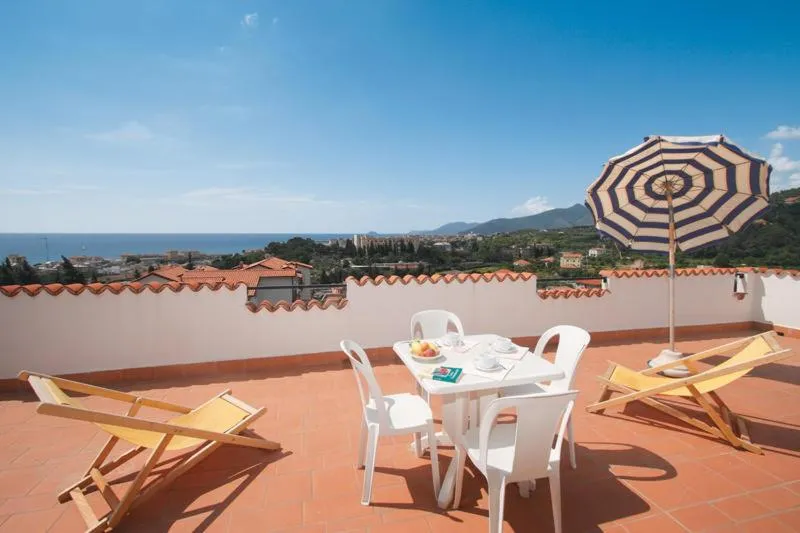Terrazza con tavolo, sedie, sdraio e ombrellone con vista sul mare e sulle colline