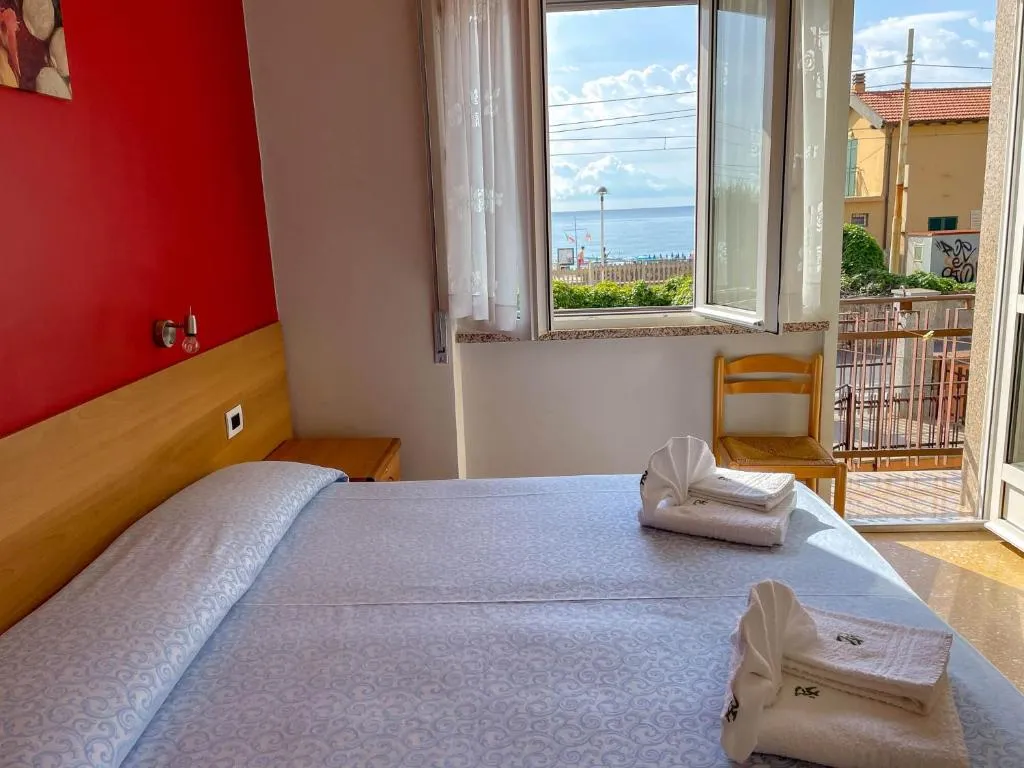 Camera matrimoniale con parete rossa e finestra con vista sul mare