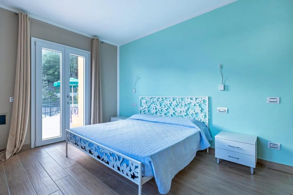 Camera da letto con parete azzurra, letto matrimoniale e porta finestra sul terrazzo