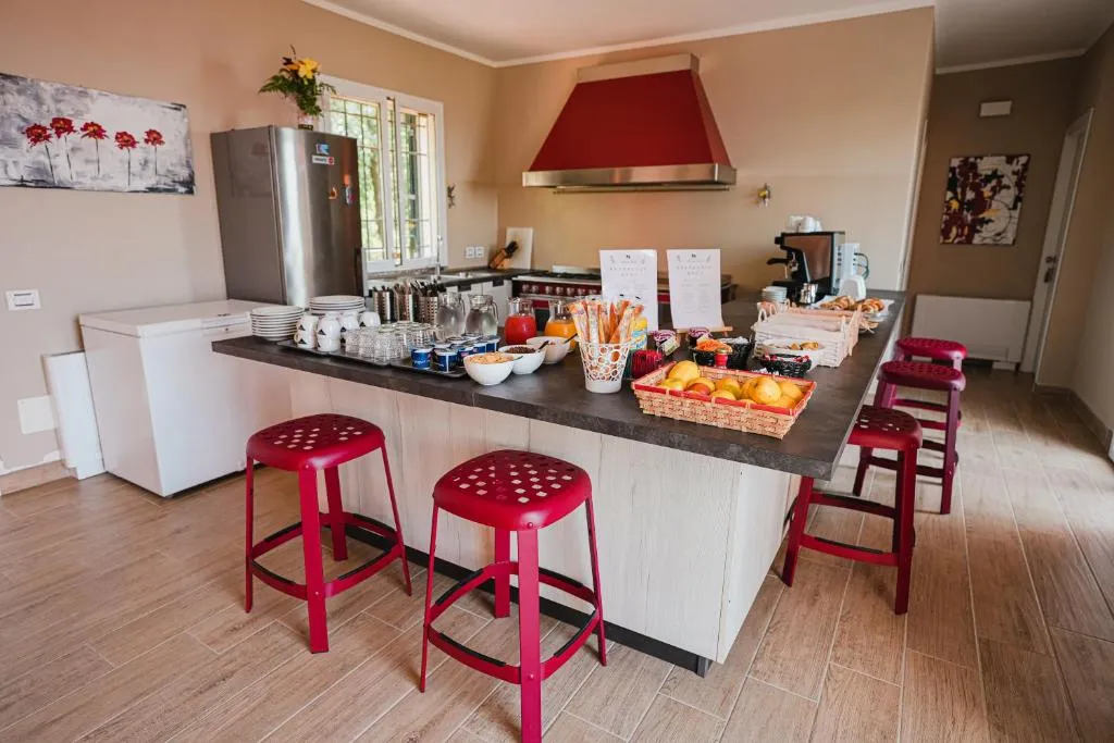 Sala colazione con buffet, frutta fresca e sgabelli rossi al bancone