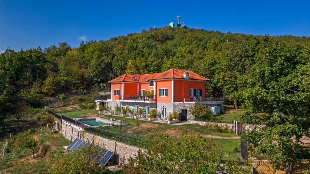 Vista aerea della villa arancione sulla collina con piscina e prato verde