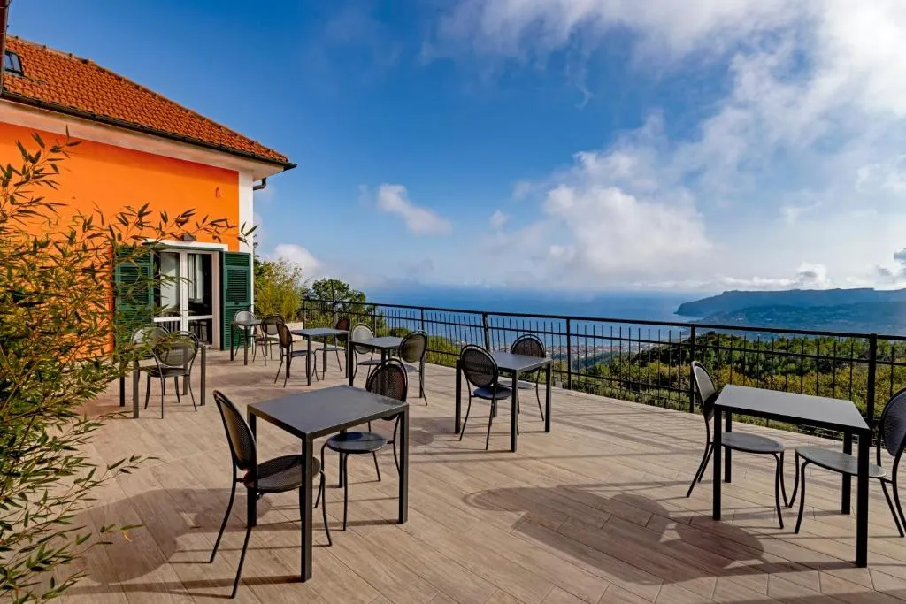 Terrazza ristorante con tavoli e sedie affacciata sul mare e la costa