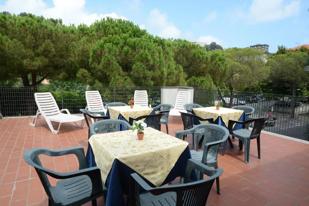 Terrazza esterna con tavoli, sedie e lettini circondata da pini
