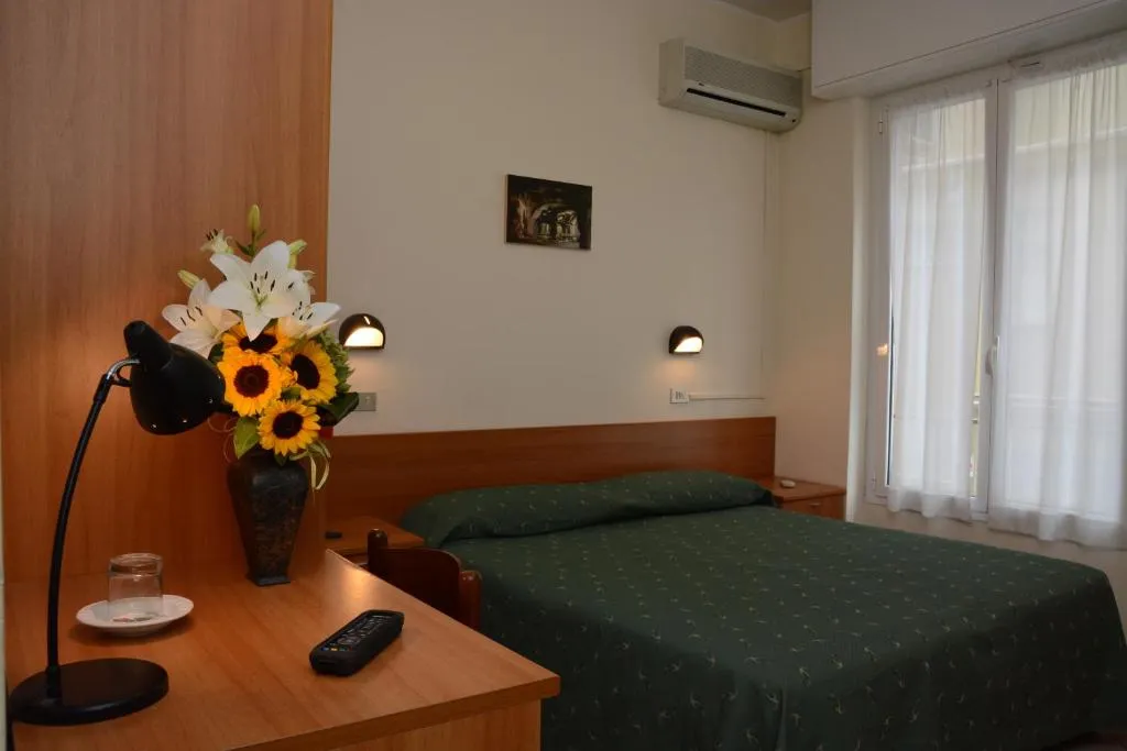 Camera con aria condizionata, scrivania in legno con fiori e letto verde