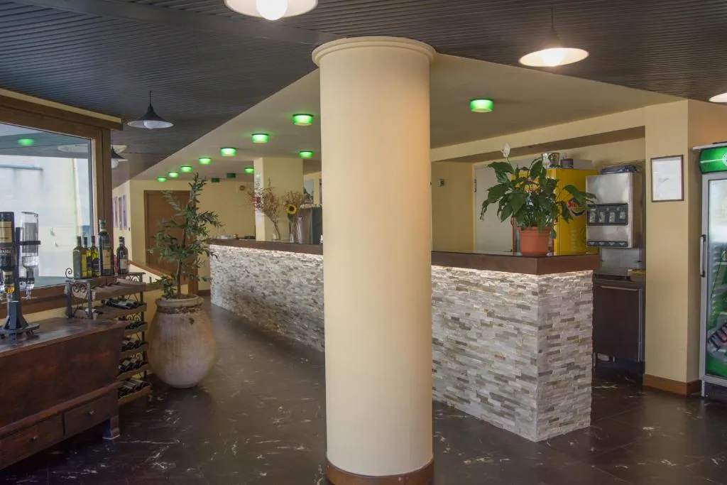 Hall dell'hotel con reception in pietra, colonna centrale e area bar