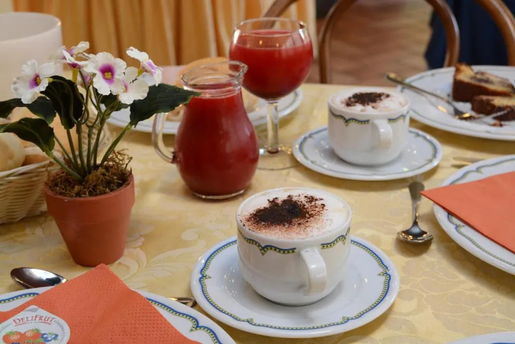 Tavolo per la colazione con cappuccino, succo rosso e dolci
