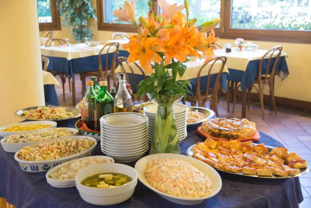 Buffet con piatti di insalate, torte e pizza decorato con fiori d'arancio
