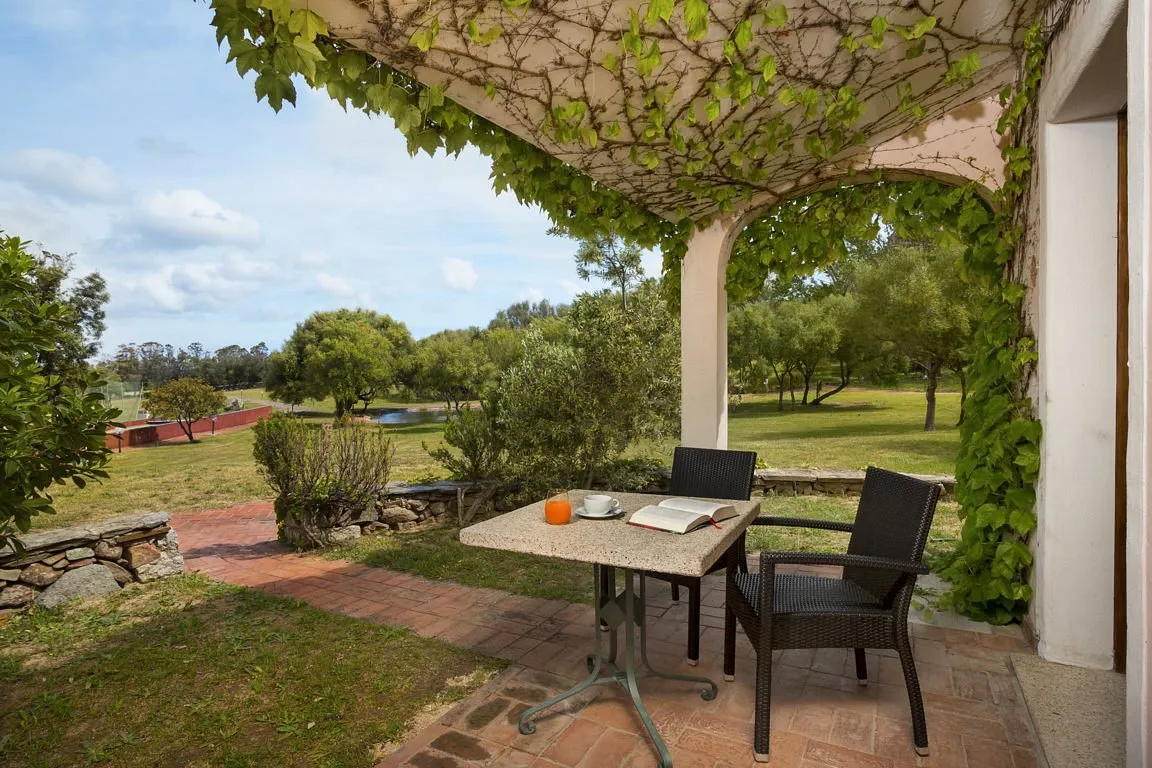 Terrazza con tavolo, sedie e pergolato verde affacciata sul giardino