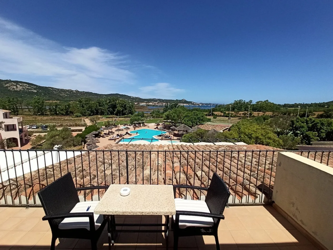 Vista panoramica dal balcone sulla piscina, il verde e la laguna della Sardegna