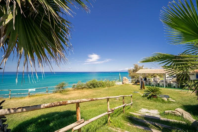 Giardino fronte mare con palme e gazebo affacciato sul mare turchese