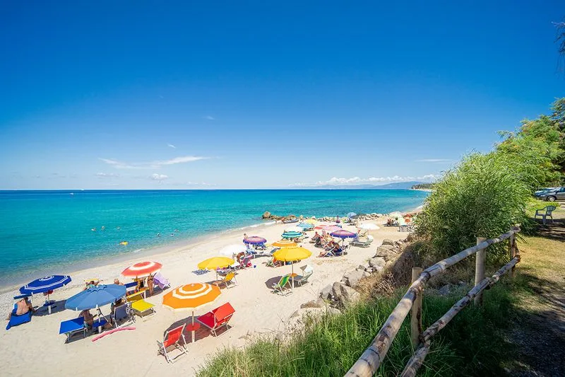 Spiaggia sabbiosa con ombrelloni colorati e mare cristallino