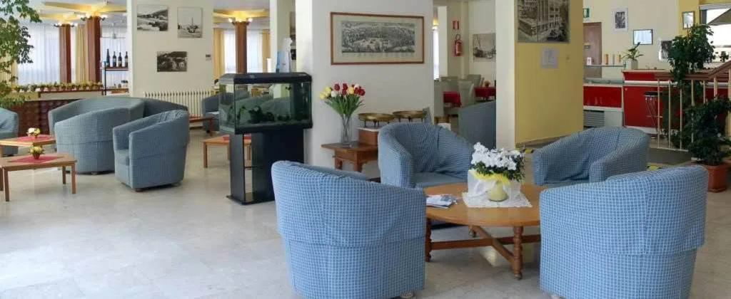 Hall dell'hotel con poltrone azzurre, acquario e tavolino in legno