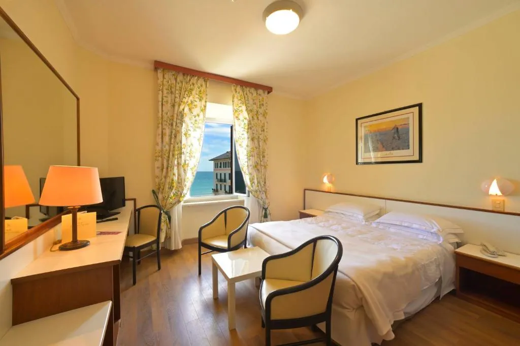 Camera con letto matrimoniale, poltroncine e finestra con vista sul mare