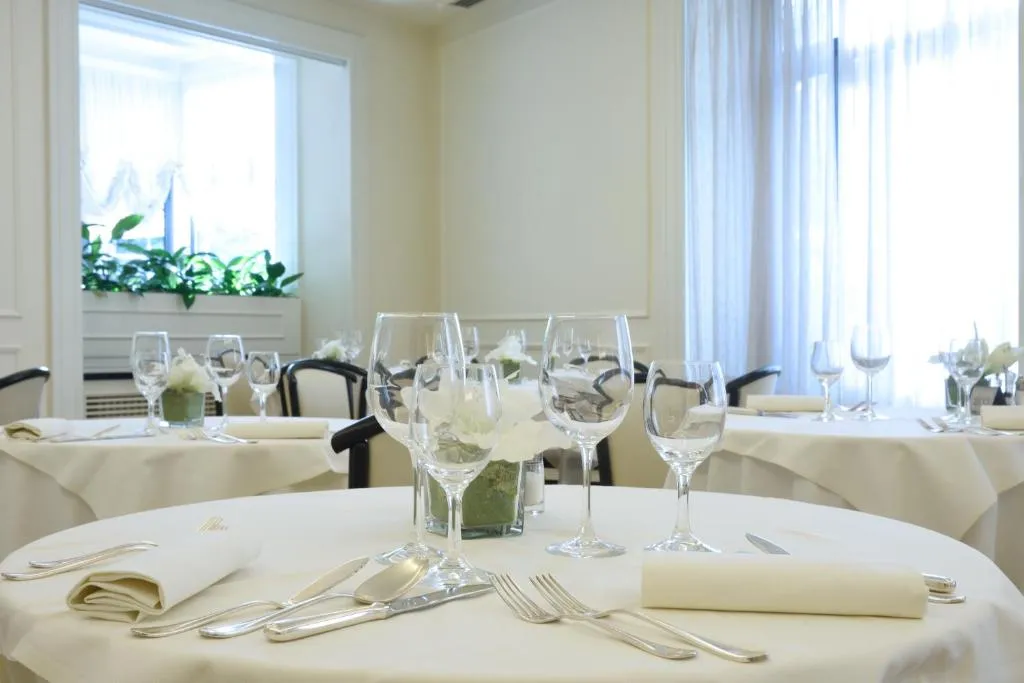 Tavolo del ristorante apparecchiato con tovaglia chiara, bicchieri di vino e decorazione floreale bianca