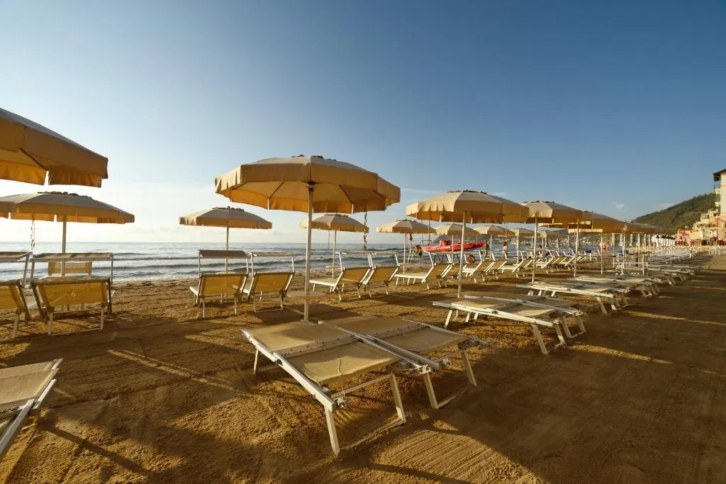 Spiaggia attrezzata con file di ombrelloni e lettini sulla sabbia al tramonto