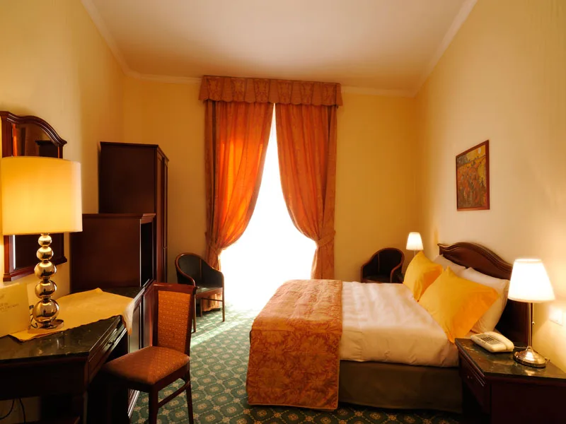 Camera elegante con letto matrimoniale, arredi in legno scuro e tende arancioni