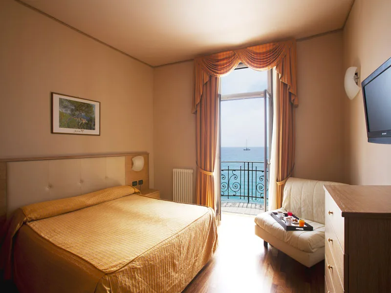 Camera matrimoniale con divano, TV e balcone con vista mare