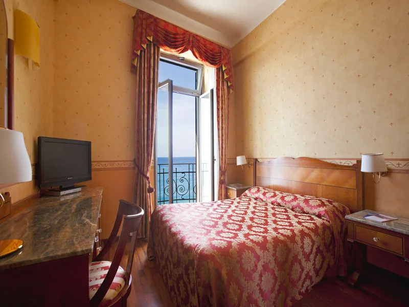 Camera con letto matrimoniale dal copriletto damascato e finestra sul mare