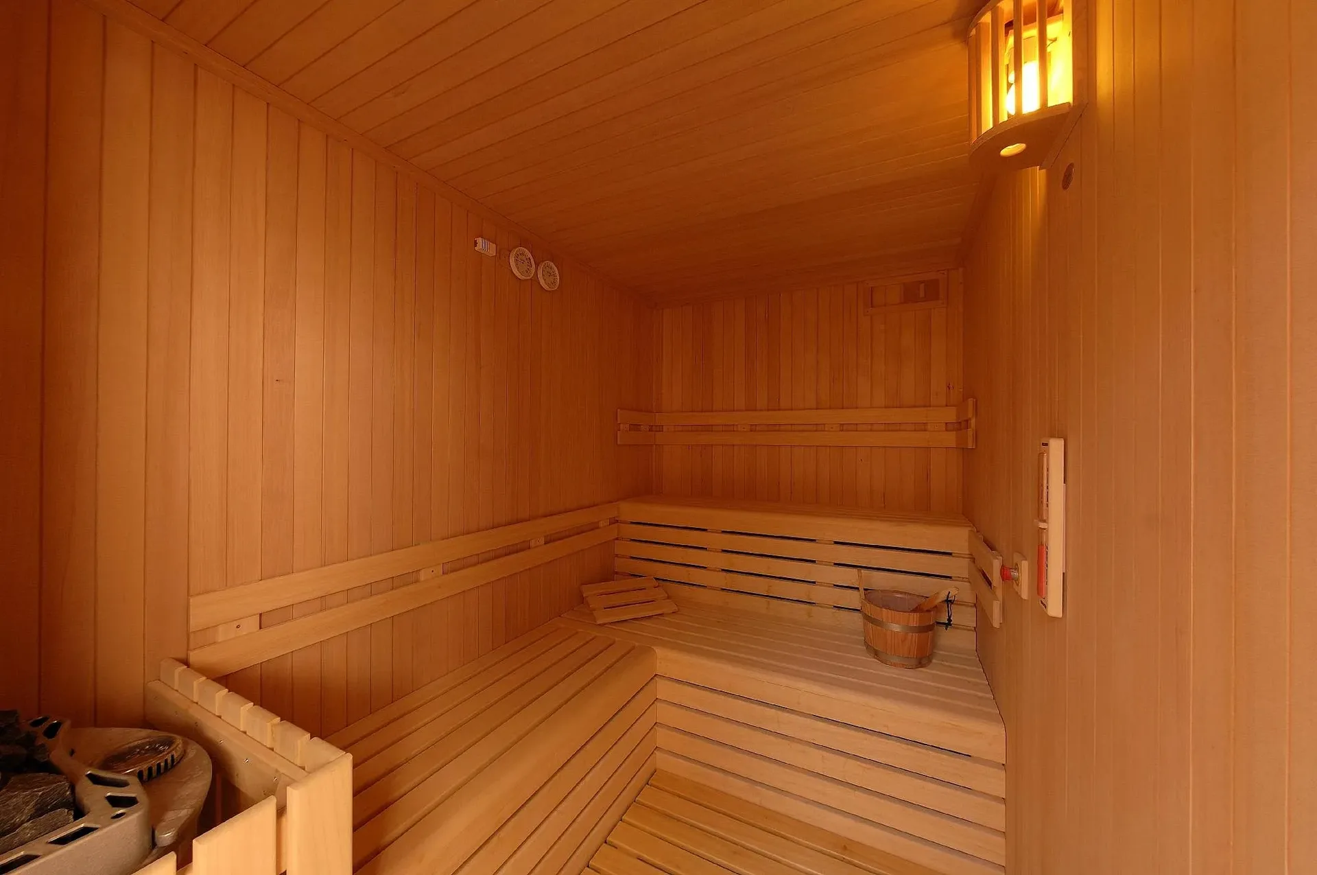 Sauna in legno con panche, secchio e lampada calda nella zona benessere
