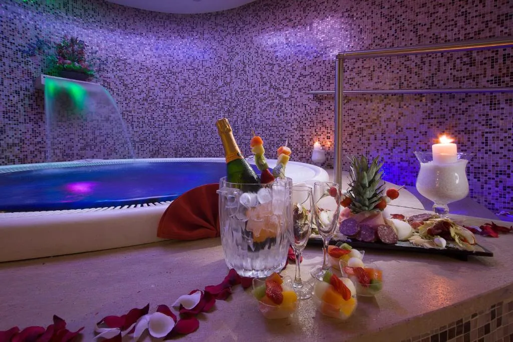 Allestimento romantico nella spa con champagne, frutta e candele accanto alla vasca idromassaggio