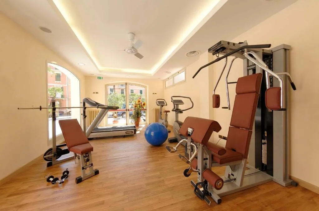 Palestra dell'hotel con attrezzi cardio e macchinari per pesi in ambiente luminoso