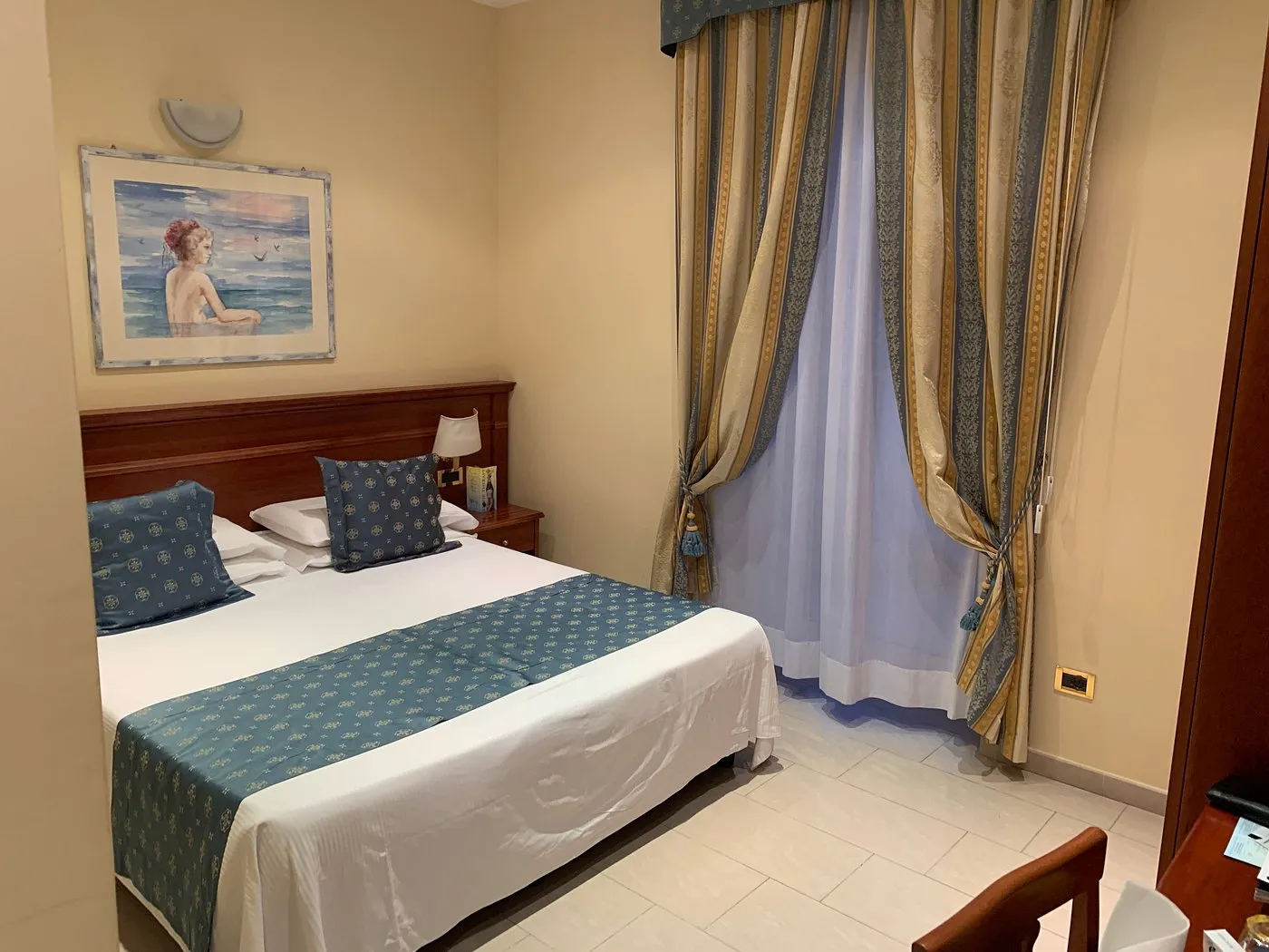Camera classica con letto matrimoniale, quadro e tende drappeggiate eleganti