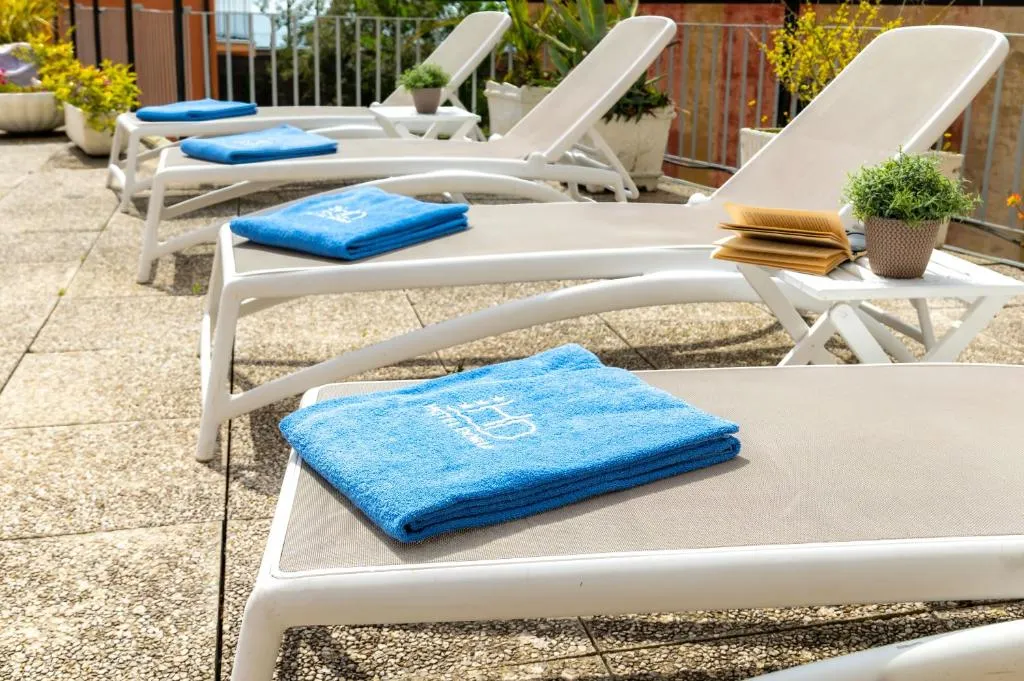 Lettini prendisole bianchi con asciugamani blu sulla terrazza