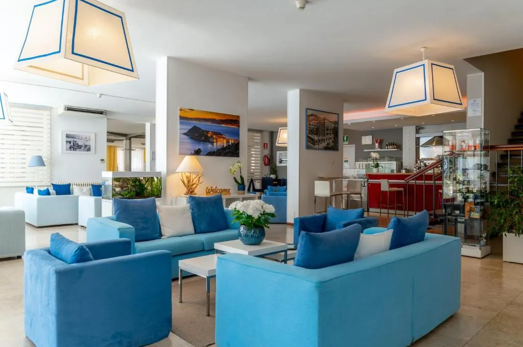 Ampia hall con divani blu, lampade decorative e bar sullo sfondo