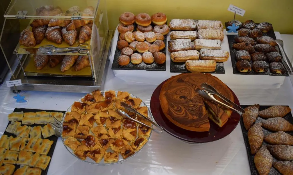 Buffet di dolci con cornetti, crostate, bomboloni e torta