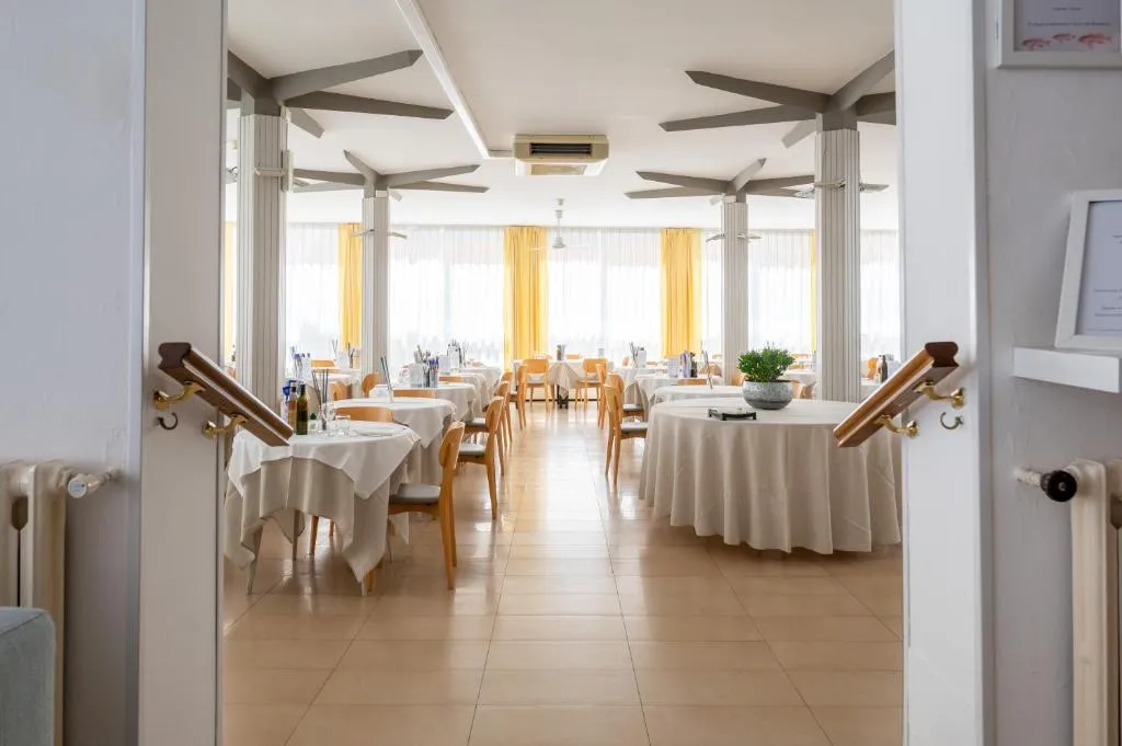 Sala ristorante luminosa con tavoli apparecchiati e tende gialle