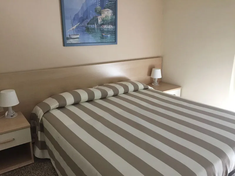 Camera con letto matrimoniale a righe e comodini in legno chiaro
