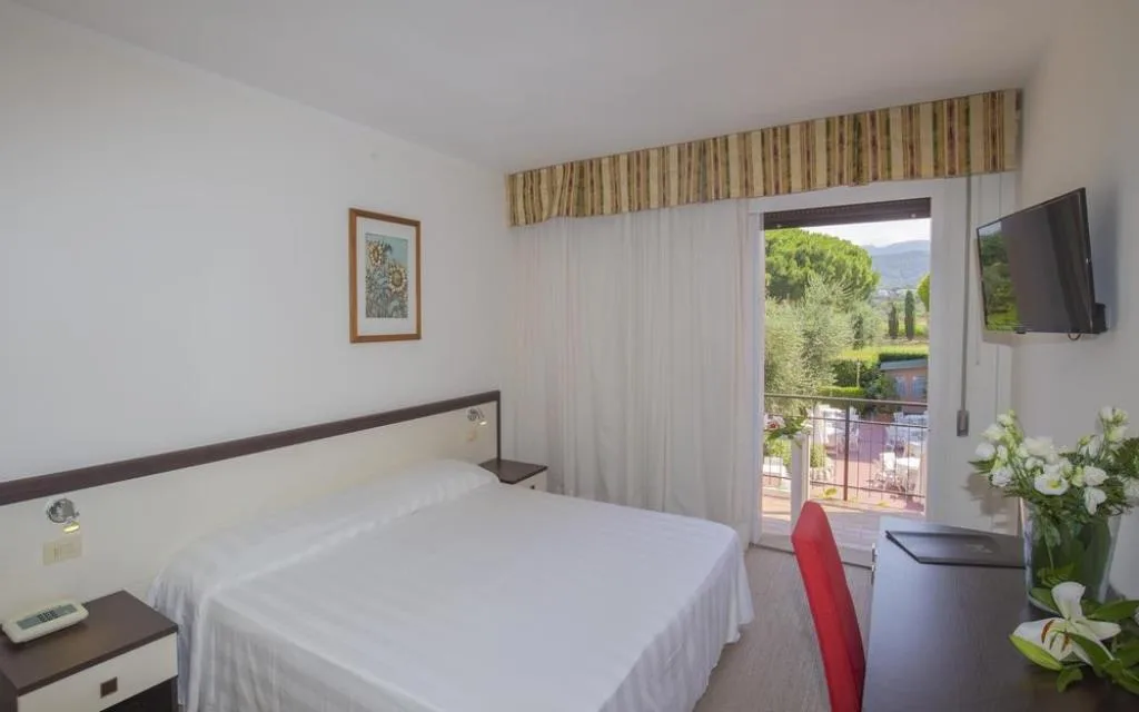 Camera luminosa con letto matrimoniale, TV e balcone con vista sul giardino