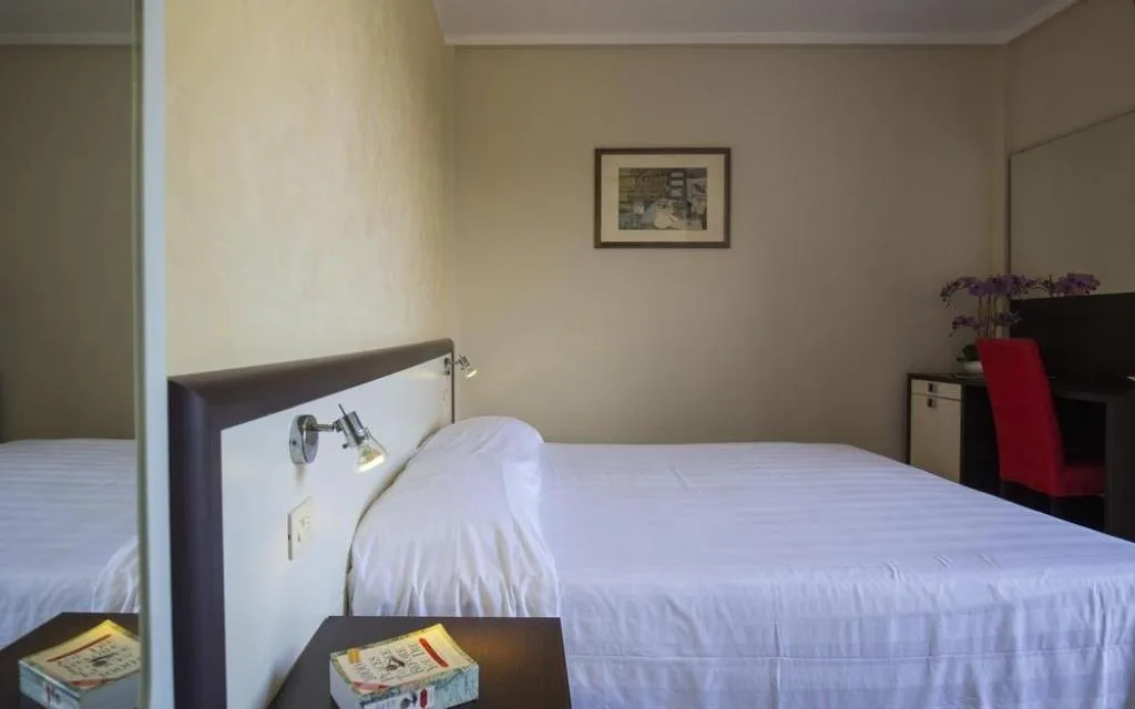 Camera con letto matrimoniale, specchio e scrivania con sedia rossa