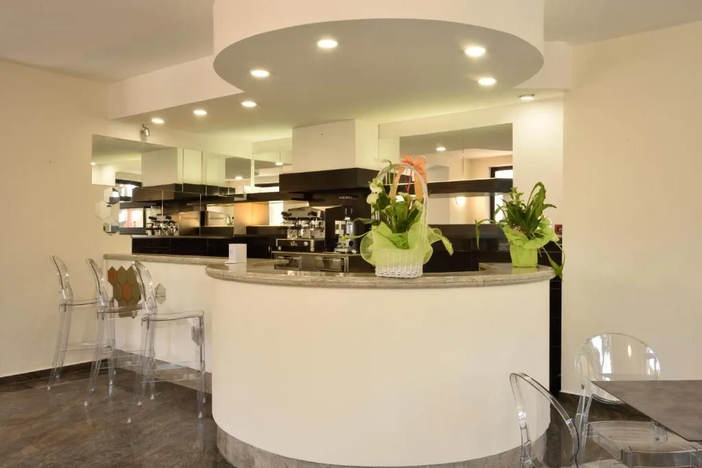Bar dell'hotel con bancone curvo, sedie trasparenti e piante decorative