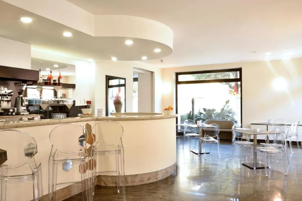 Area bar e sala colazione con bancone, sedie trasparenti e tavoli