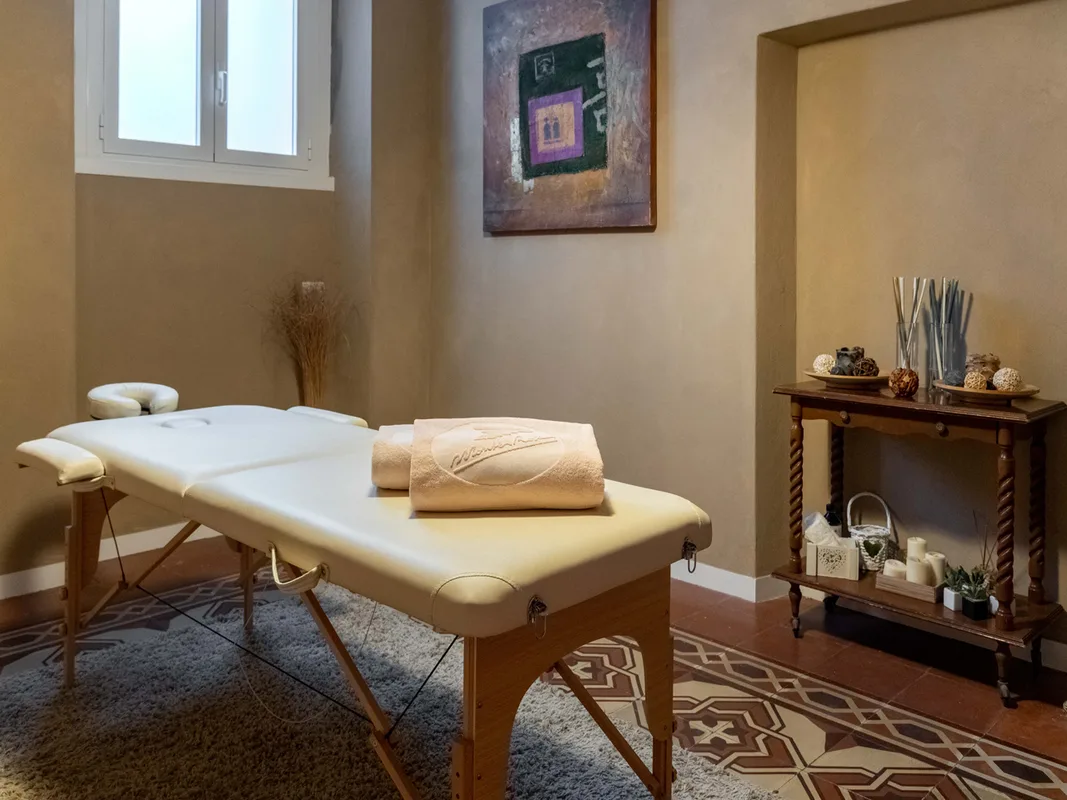 Sala massaggi della spa con lettino, asciugamani e dettagli decorativi su pavimento in cementine