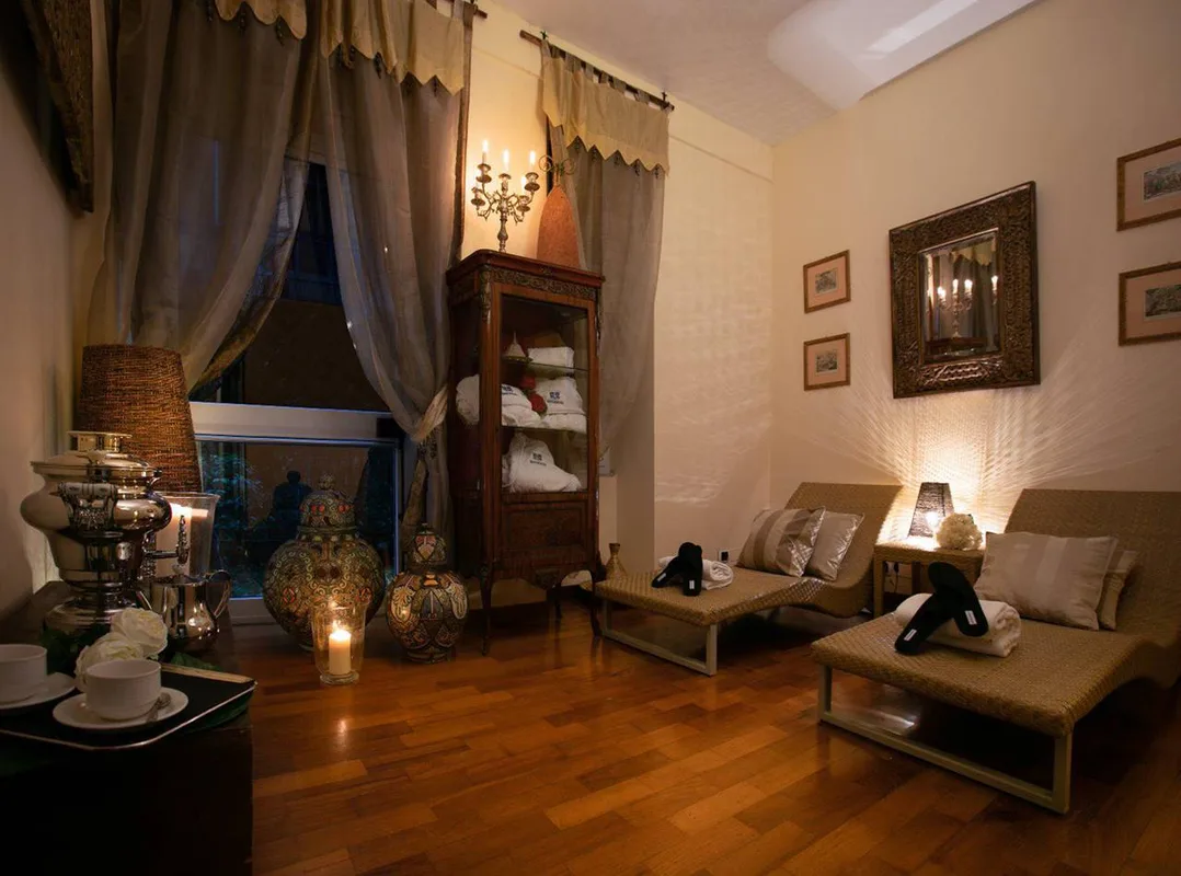 Area relax spa con chaise longue in vimini, candele, mobile antico con accappatoi e atmosfera soffusa