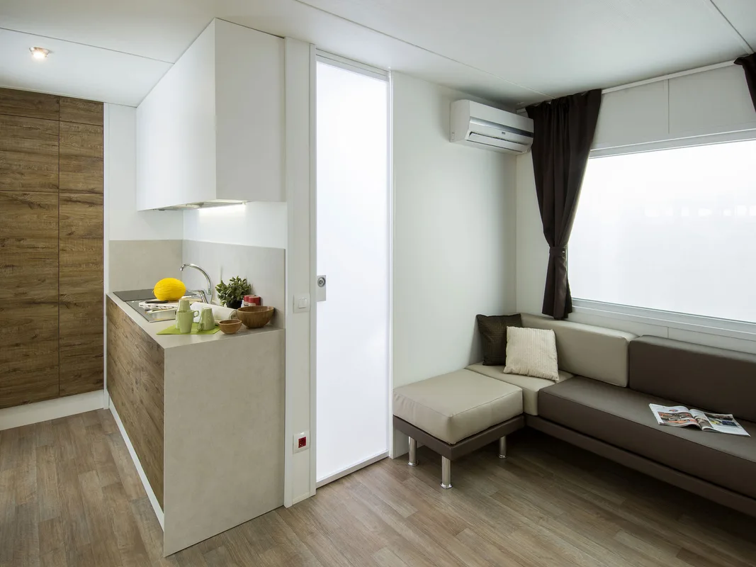 Interno di casa mobile con angolo cottura e divano grigio