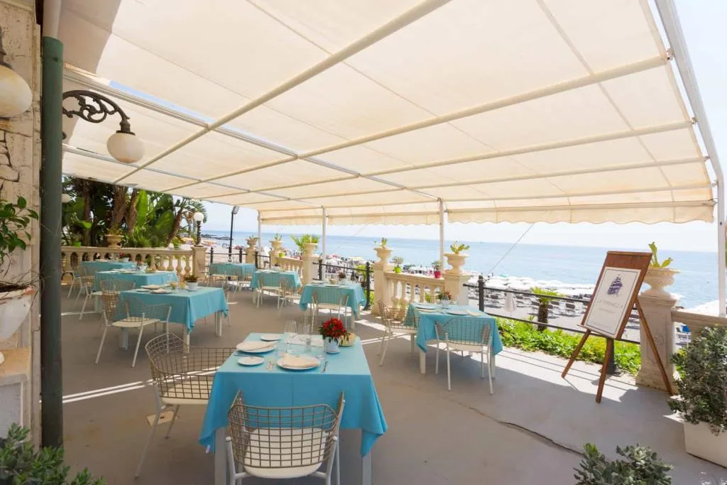 Terrazza ristorante con tavoli azzurri vista mare