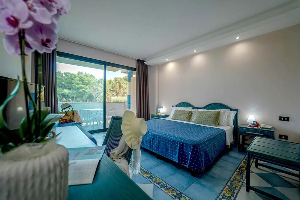 Camera elegante con letto matrimoniale, arredi blu e colazione servita sul balcone