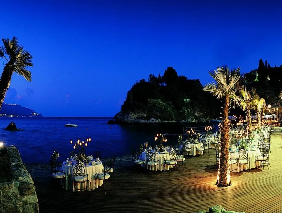 Cena romantica in riva al mare al crepuscolo con tavoli illuminati da candele