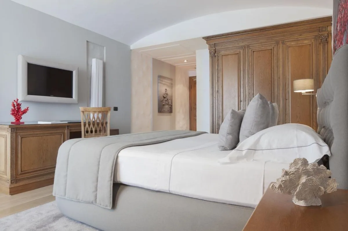 Camera elegante con letto matrimoniale, testiera in legno intagliato e dettagli in corallo rosso