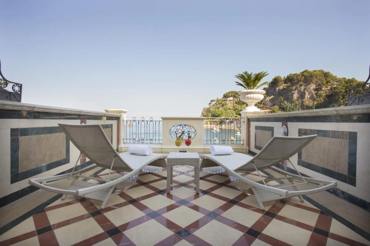 Terrazza con lettini prendisole e pavimento a scacchi vista mare e scogliera